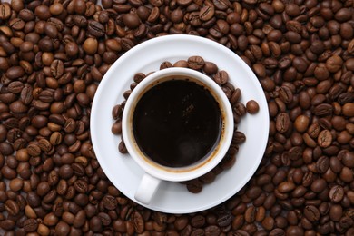 Photo of Aromatic coffee in cup, saucer and beans, top view