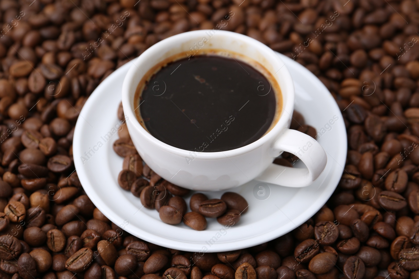 Aromatic coffee in cup, saucer and beans, closeup Photo of Aromatic coffee in cup, saucer and beans, closeup