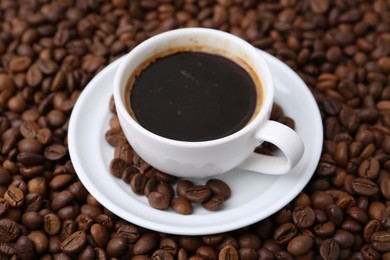 Photo of Aromatic coffee in cup, saucer and beans, closeup
