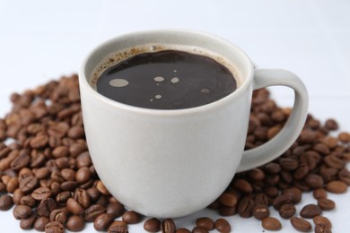Photo of Aromatic coffee in cup and beans on white background, closeup