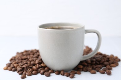 Photo of Aromatic coffee in cup and beans on white background, closeup