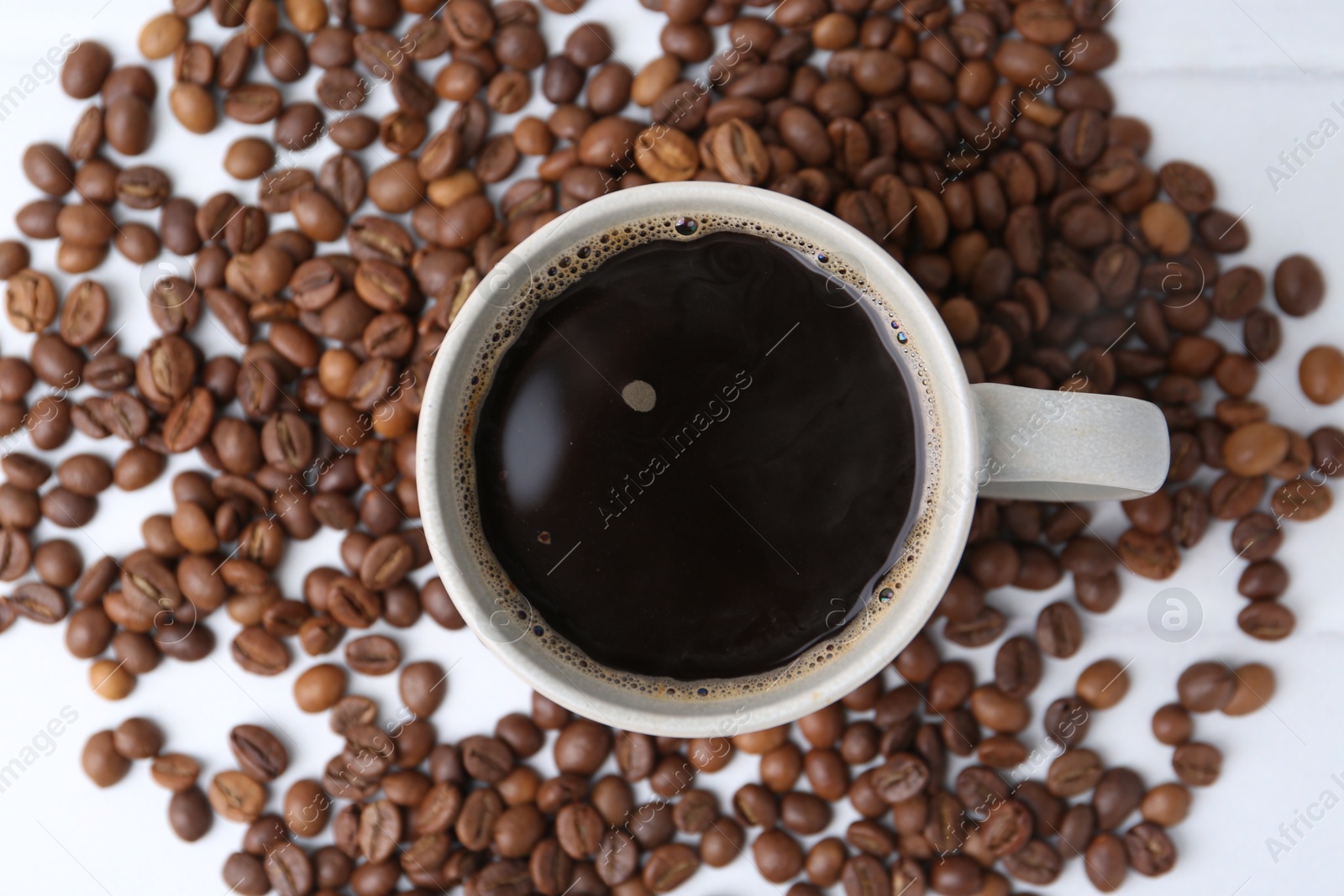 Aromatic coffee in cup and beans on white table, top view Photo of Aromatic coffee in cup and beans on white table, top view