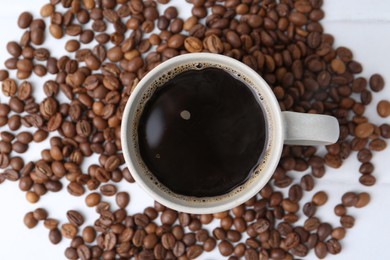 Photo of Aromatic coffee in cup and beans on white table, top view