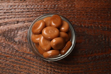 Photo of Many tasty caramel candies on wooden table, top view