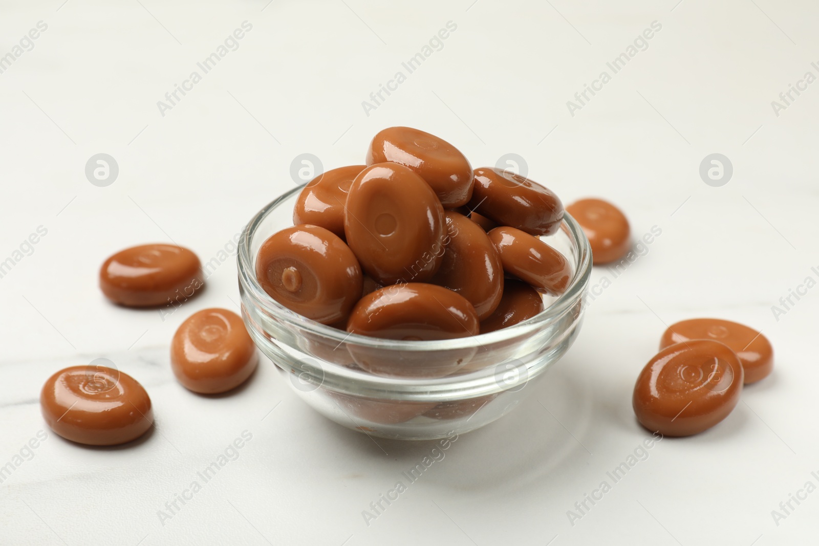Photo of Many tasty caramel candies on white table, closeup