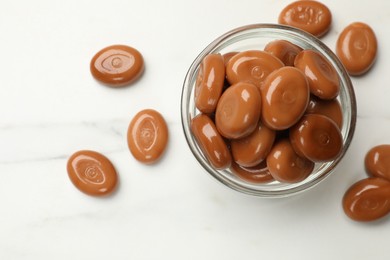 Photo of Many tasty caramel candies on white table, flat lay