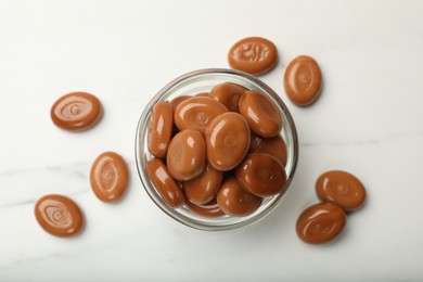 Photo of Many tasty caramel candies on white table, flat lay