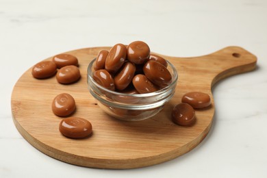 Photo of Many tasty caramel candies on white table