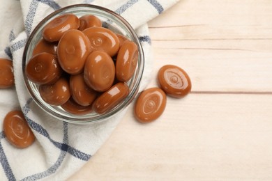 Photo of Many tasty caramel candies on white wooden table, flat lay