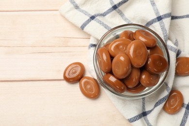 Photo of Many tasty caramel candies on white wooden table, flat lay. Space for text