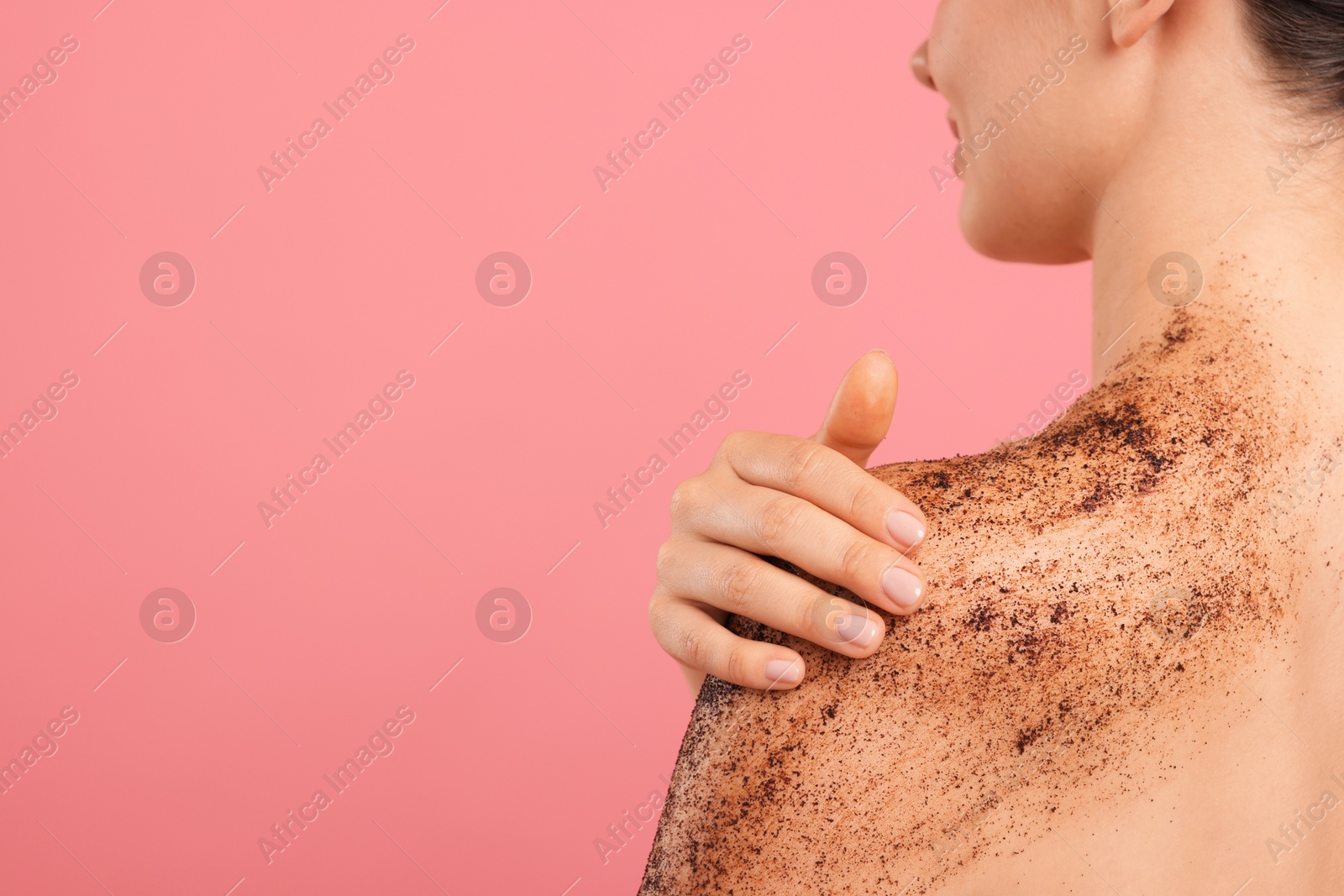 Woman applying body scrub onto her shoulder against pink background, closeup. Space for text Photo of Woman applying body scrub onto her shoulder against pink background, closeup. Space for text