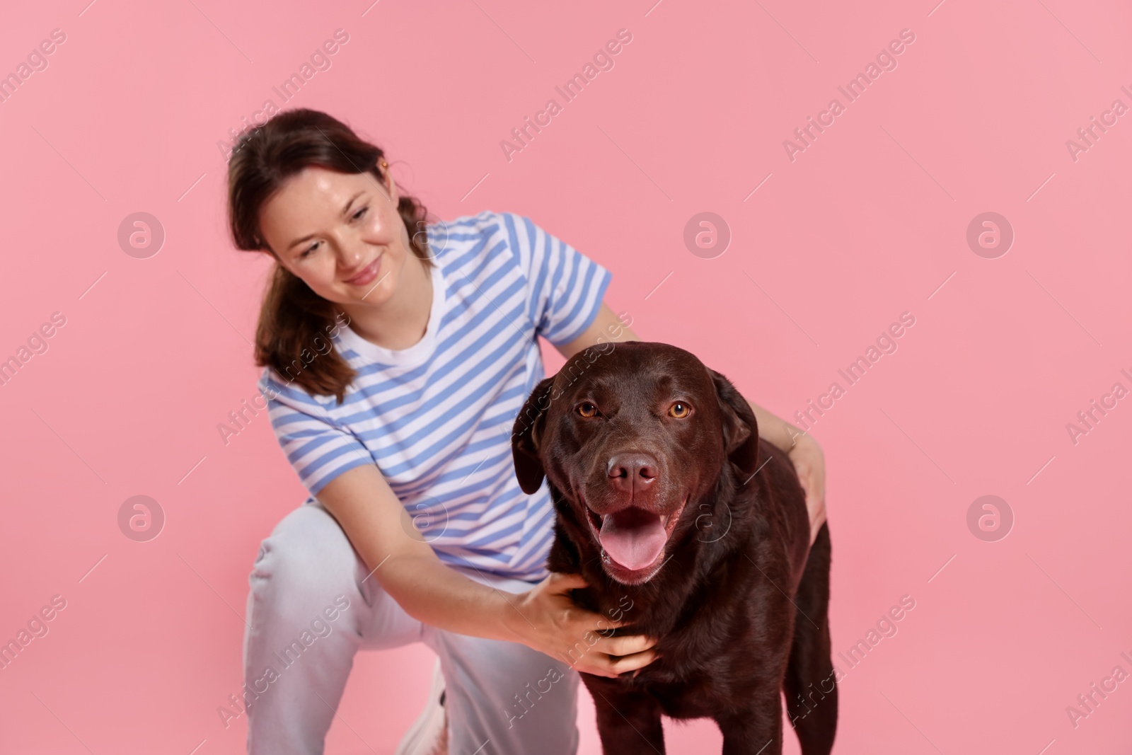 Animal training. Woman with her cute dog on pink background Photo of Animal training. Woman with her cute dog on pink background