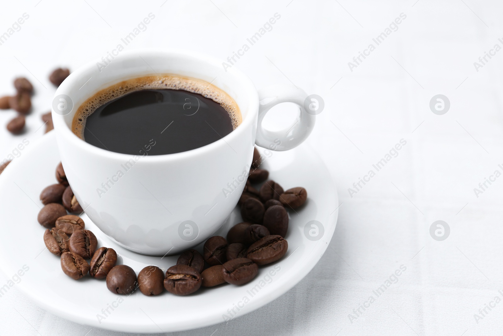 Aromatic coffee in cup and beans on white table, closeup. Space for text Photo of Aromatic coffee in cup and beans on white table, closeup. Space for text