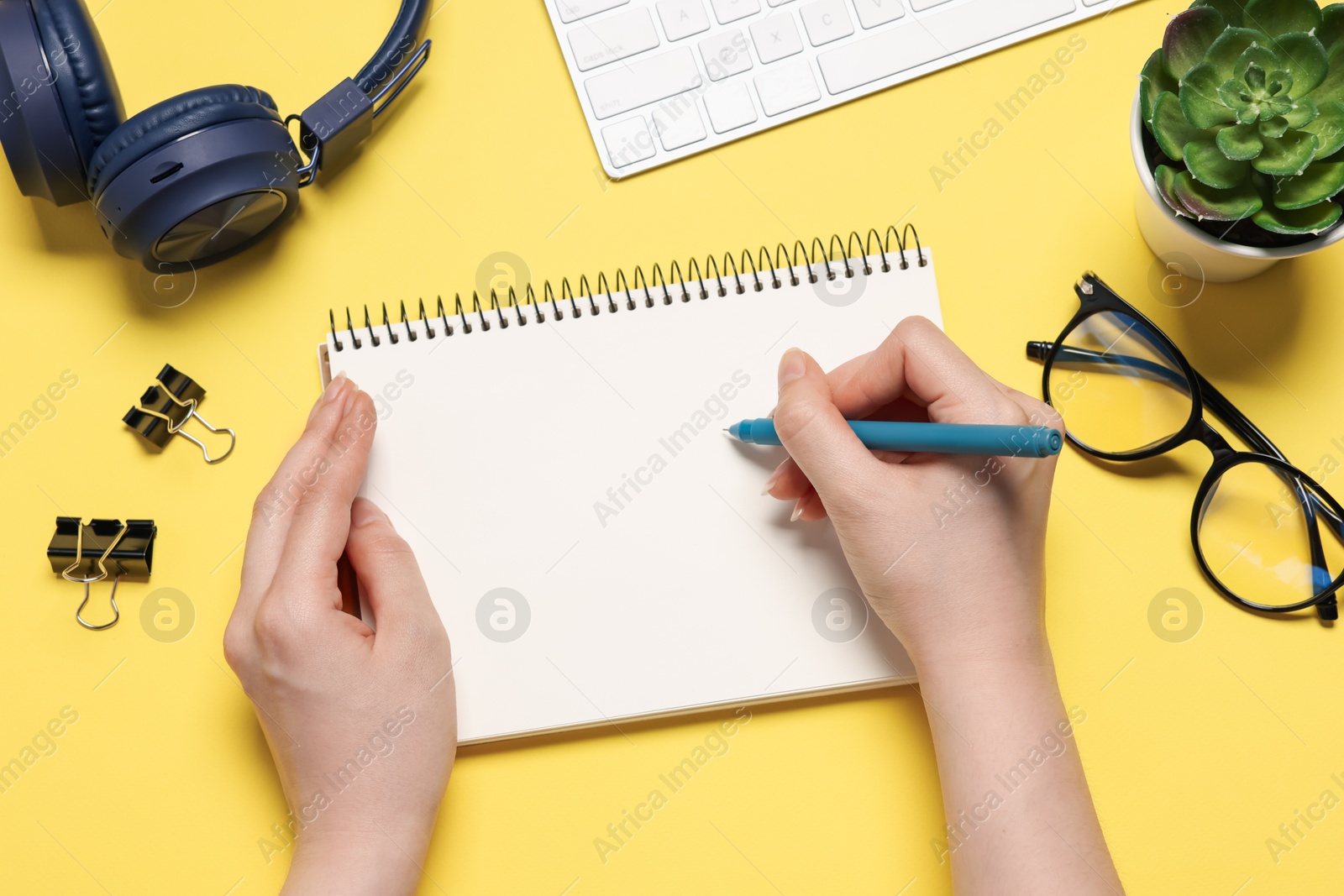 Woman with planner and stationery on yellow background, top view Photo of Woman with planner and stationery on yellow background, top view