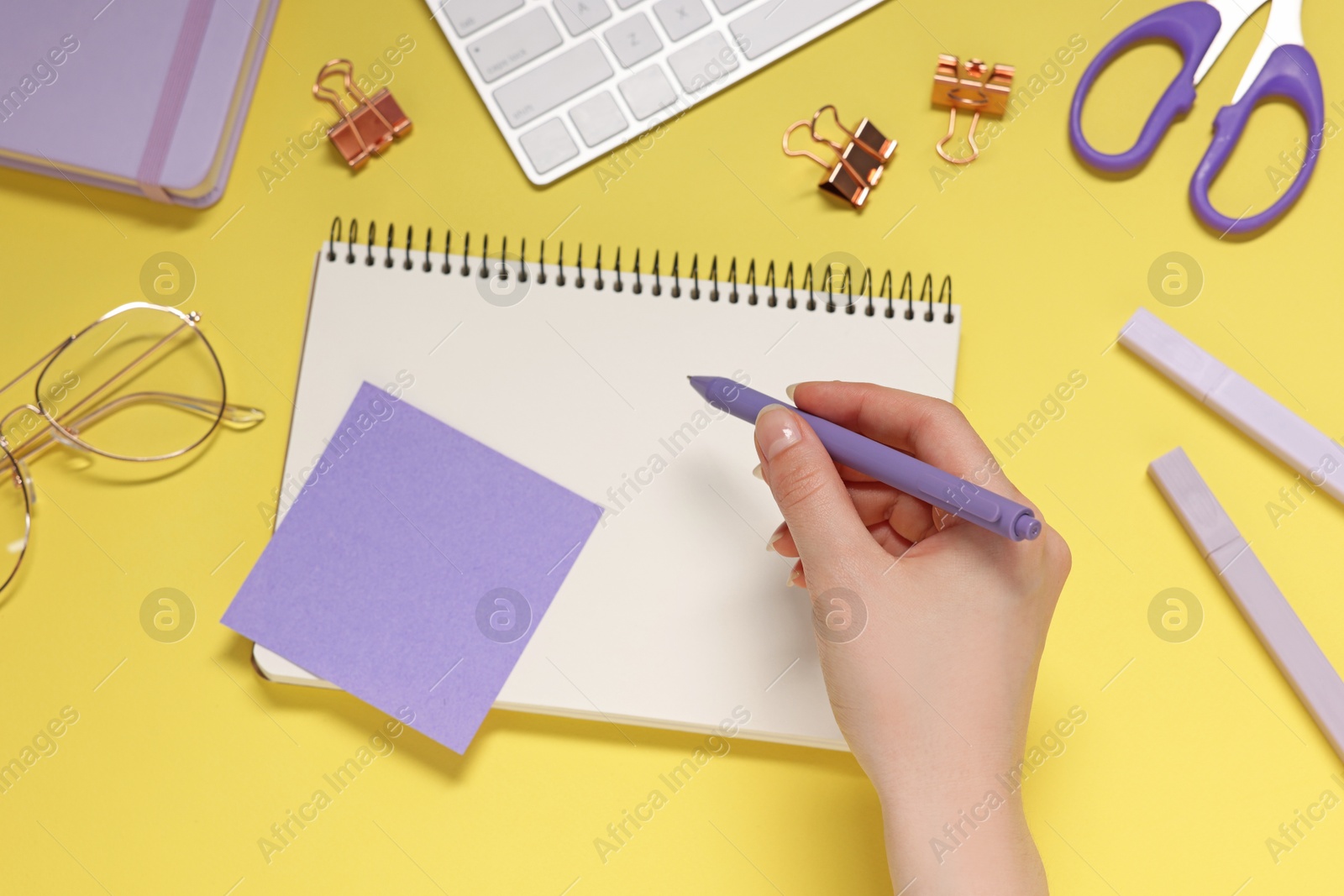Photo of Woman with planner and stationery on yellow background, top view