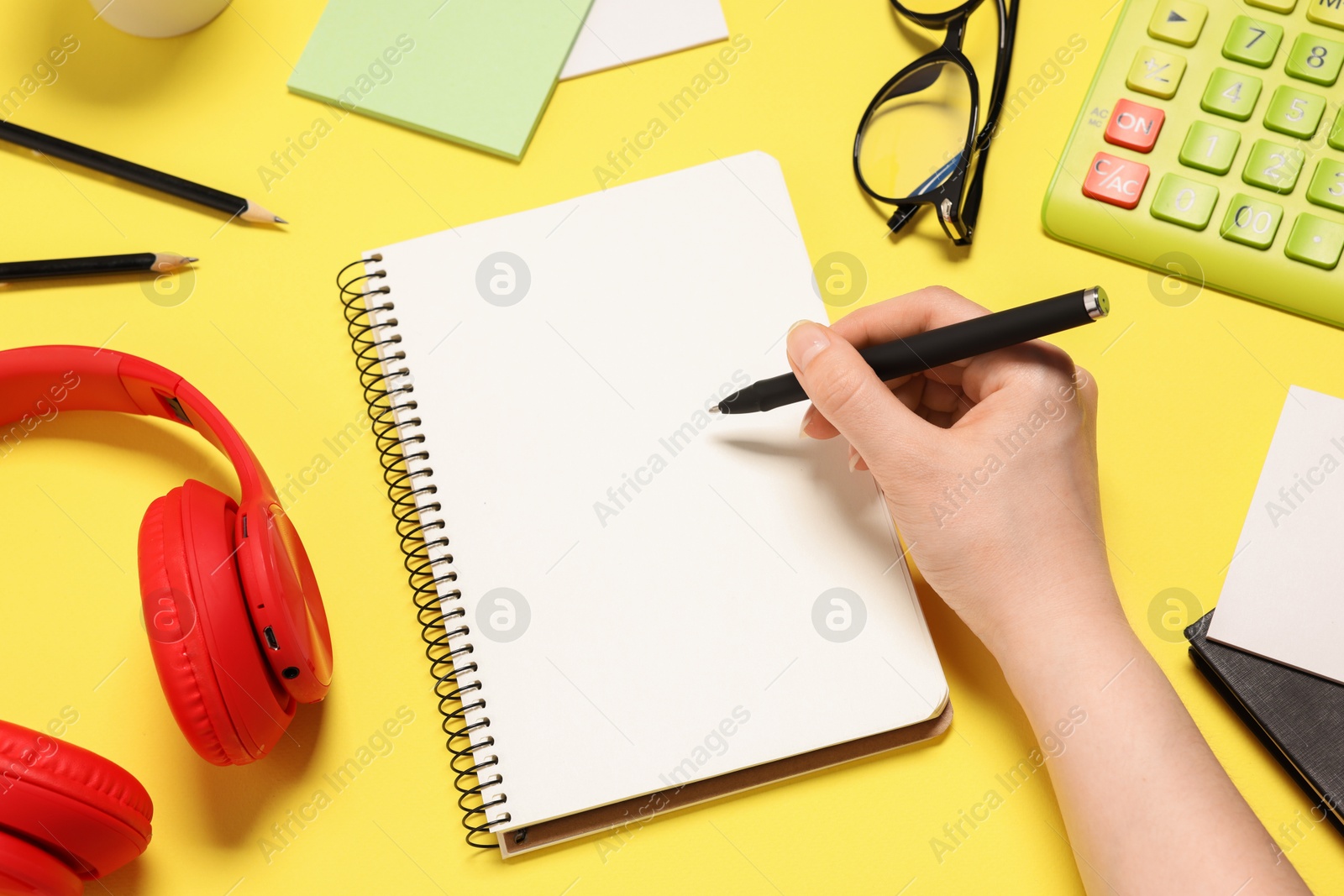 Photo of Woman with planner and stationery on yellow background, top view