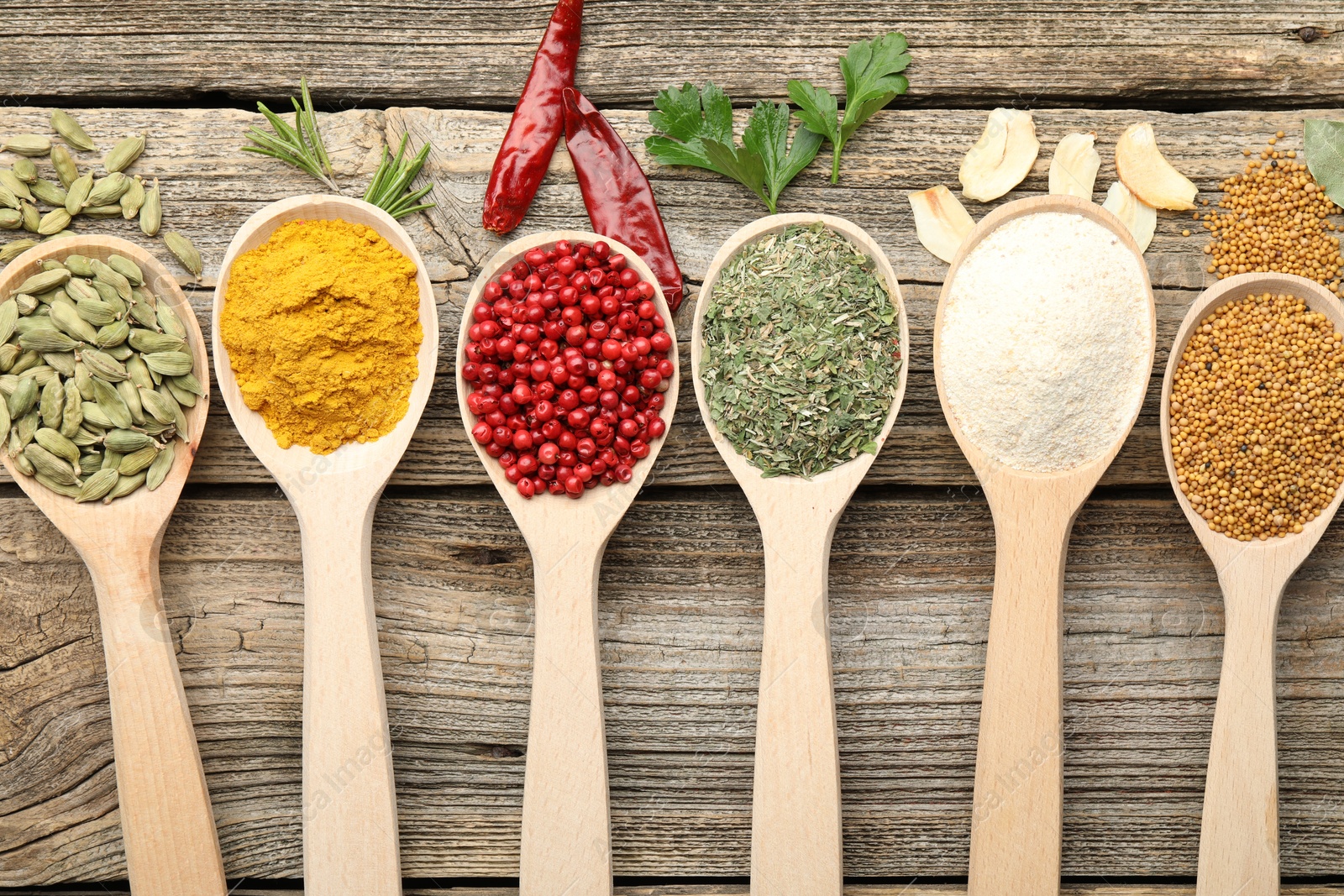 Different aromatic spices in spoons on wooden table, flat lay Photo of Different aromatic spices in spoons on wooden table, flat lay