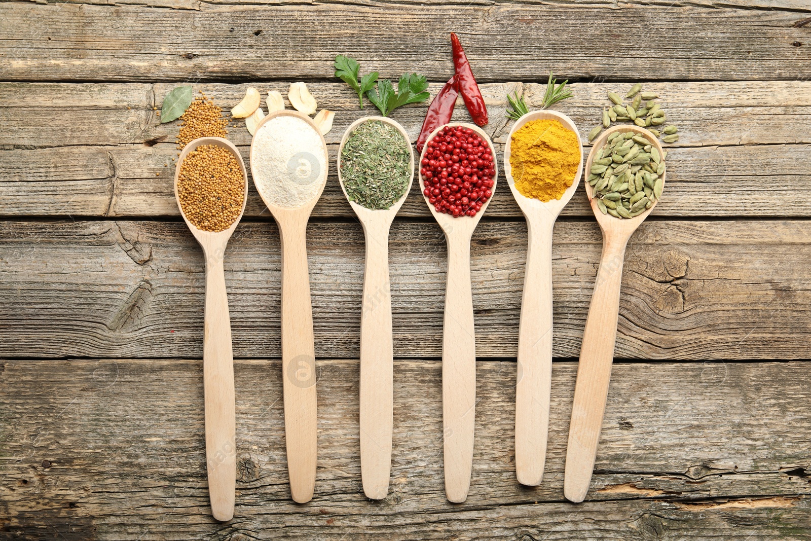 Different aromatic spices in spoons on wooden table, flat lay Photo of Different aromatic spices in spoons on wooden table, flat lay