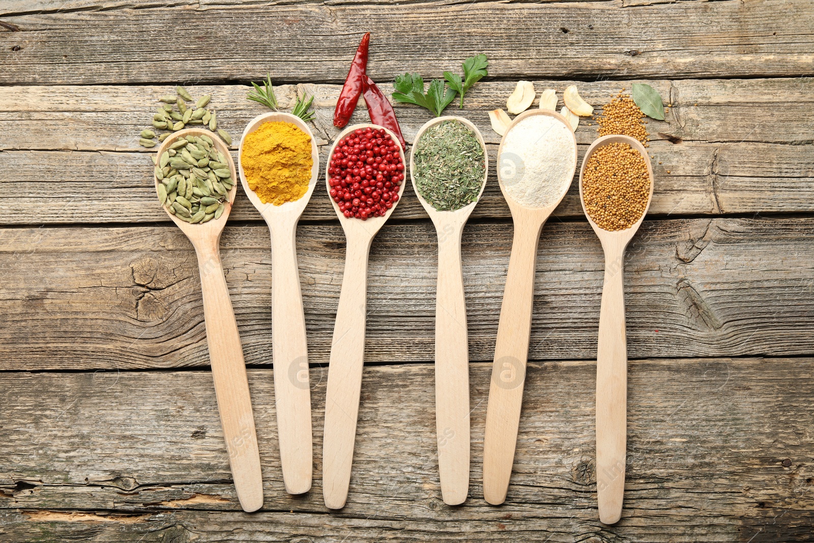 Different aromatic spices in spoons on wooden table, flat lay Photo of Different aromatic spices in spoons on wooden table, flat lay