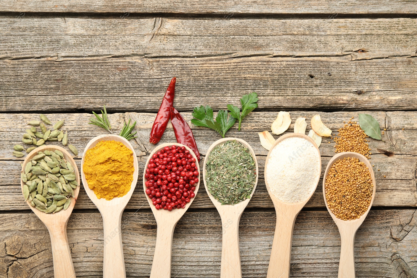 Different aromatic spices in spoons on wooden table, flat lay. Space for text Photo of Different aromatic spices in spoons on wooden table, flat lay. Space for text