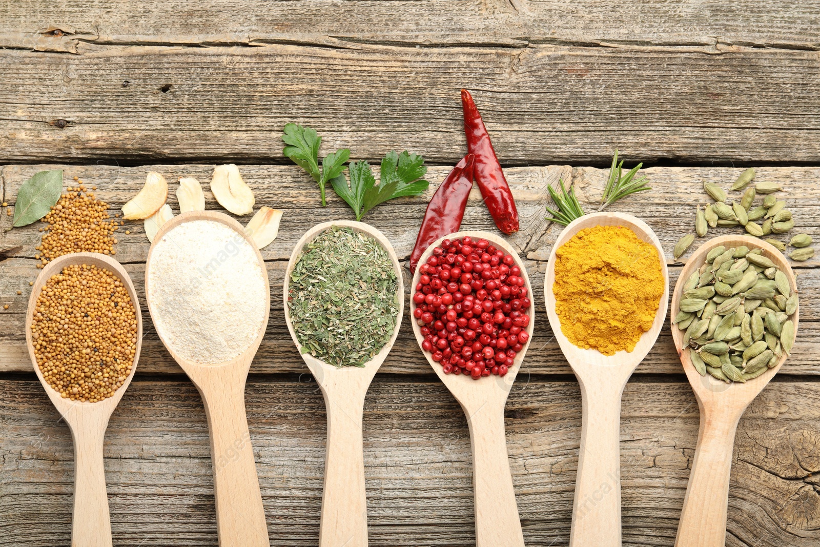 Different aromatic spices in spoons on wooden table, flat lay Photo of Different aromatic spices in spoons on wooden table, flat lay