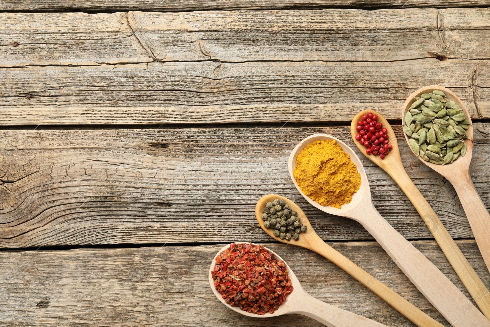 Different aromatic spices in spoons on wooden table, flat lay. Space for text Photo of Different aromatic spices in spoons on wooden table, flat lay. Space for text