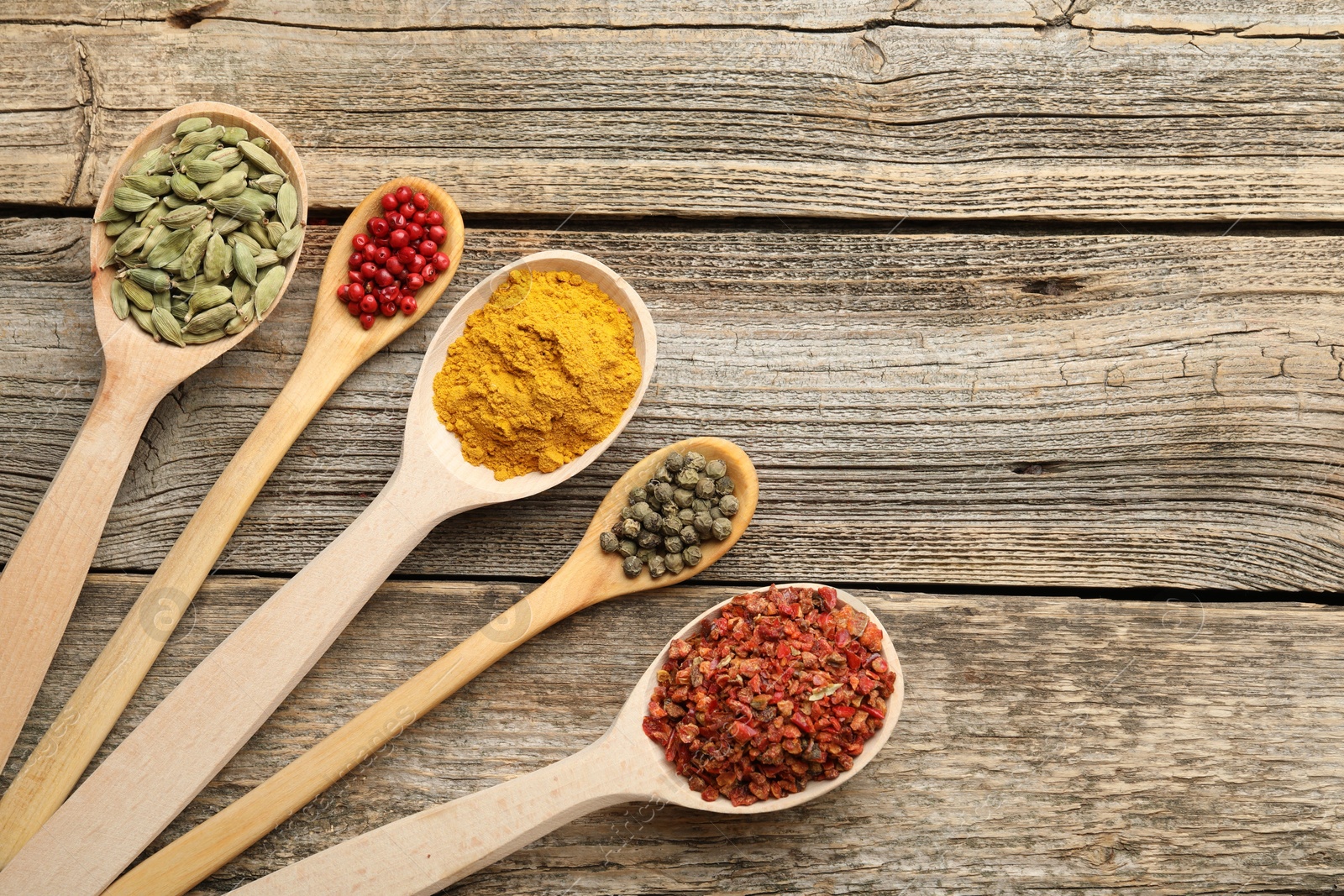 Different aromatic spices in spoons on wooden table, flat lay. Space for text Photo of Different aromatic spices in spoons on wooden table, flat lay. Space for text