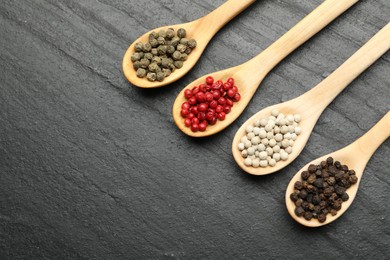 Photo of Different aromatic spices in spoons on black table, flat lay. Space for text