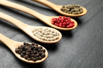 Photo of Different aromatic spices in spoons on black table, closeup