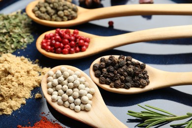 Photo of Different aromatic spices in spoons on plate, closeup