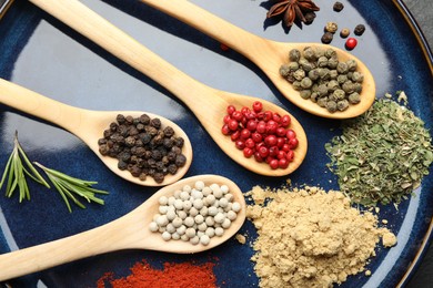 Photo of Different aromatic spices in spoons on plate, closeup