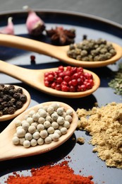 Photo of Different aromatic spices in spoons on plate, closeup