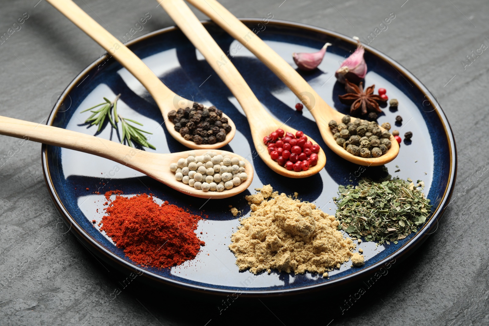 Different aromatic spices in spoons on black table, closeup Photo of Different aromatic spices in spoons on black table, closeup
