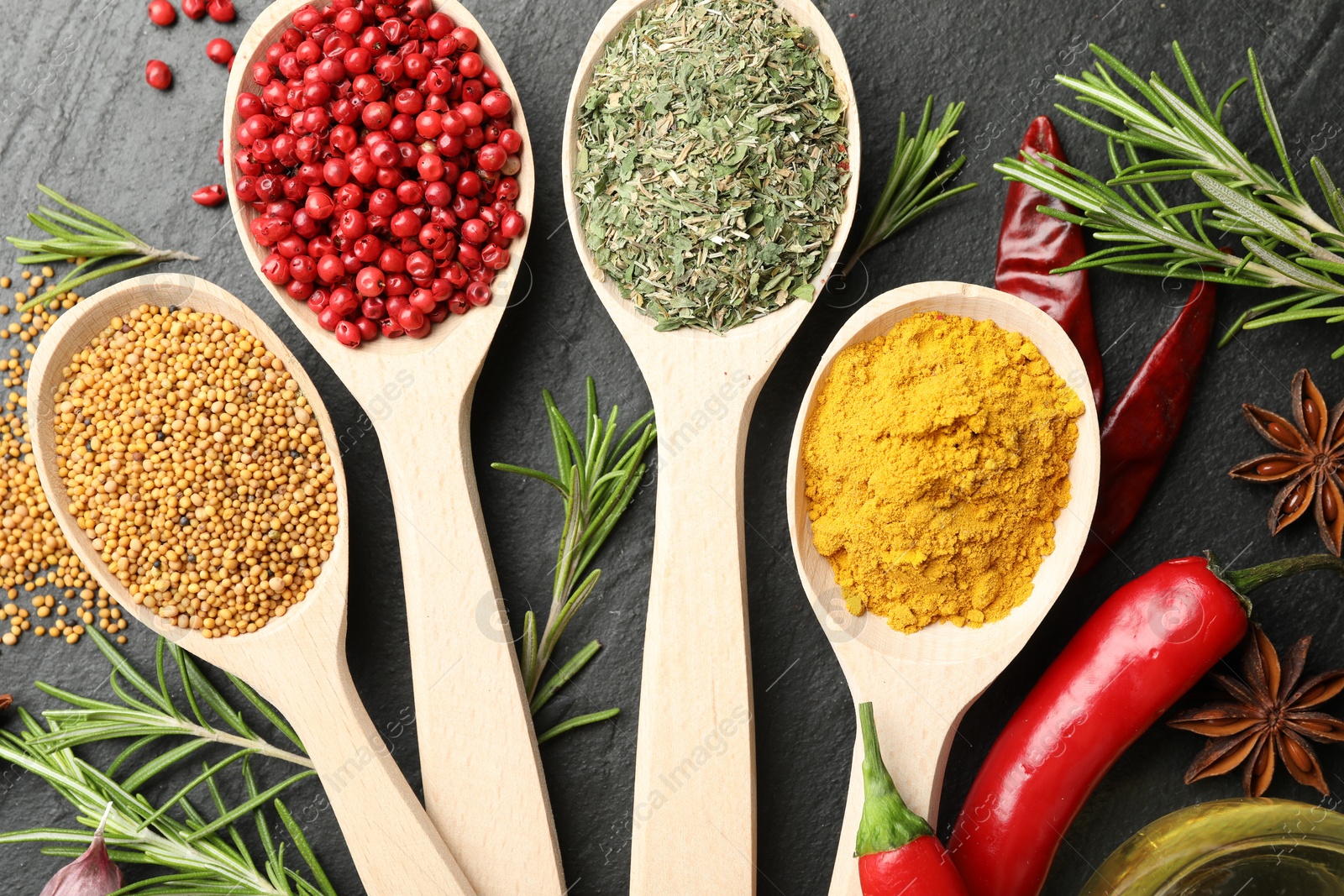 Different aromatic spices in spoons on black table, flat lay Photo of Different aromatic spices in spoons on black table, flat lay