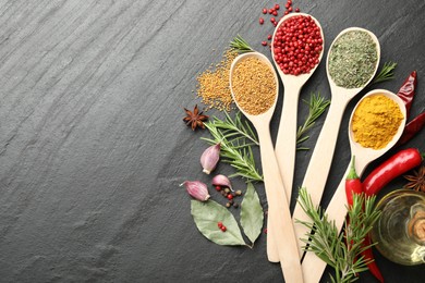 Photo of Different aromatic spices in spoons on black table, flat lay. Space for text