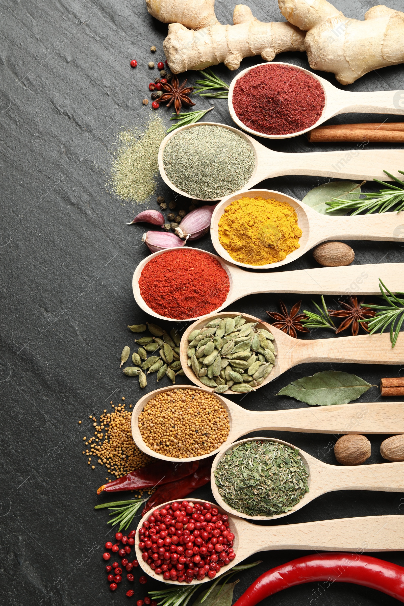 Different aromatic spices in spoons on black table, flat lay Photo of Different aromatic spices in spoons on black table, flat lay