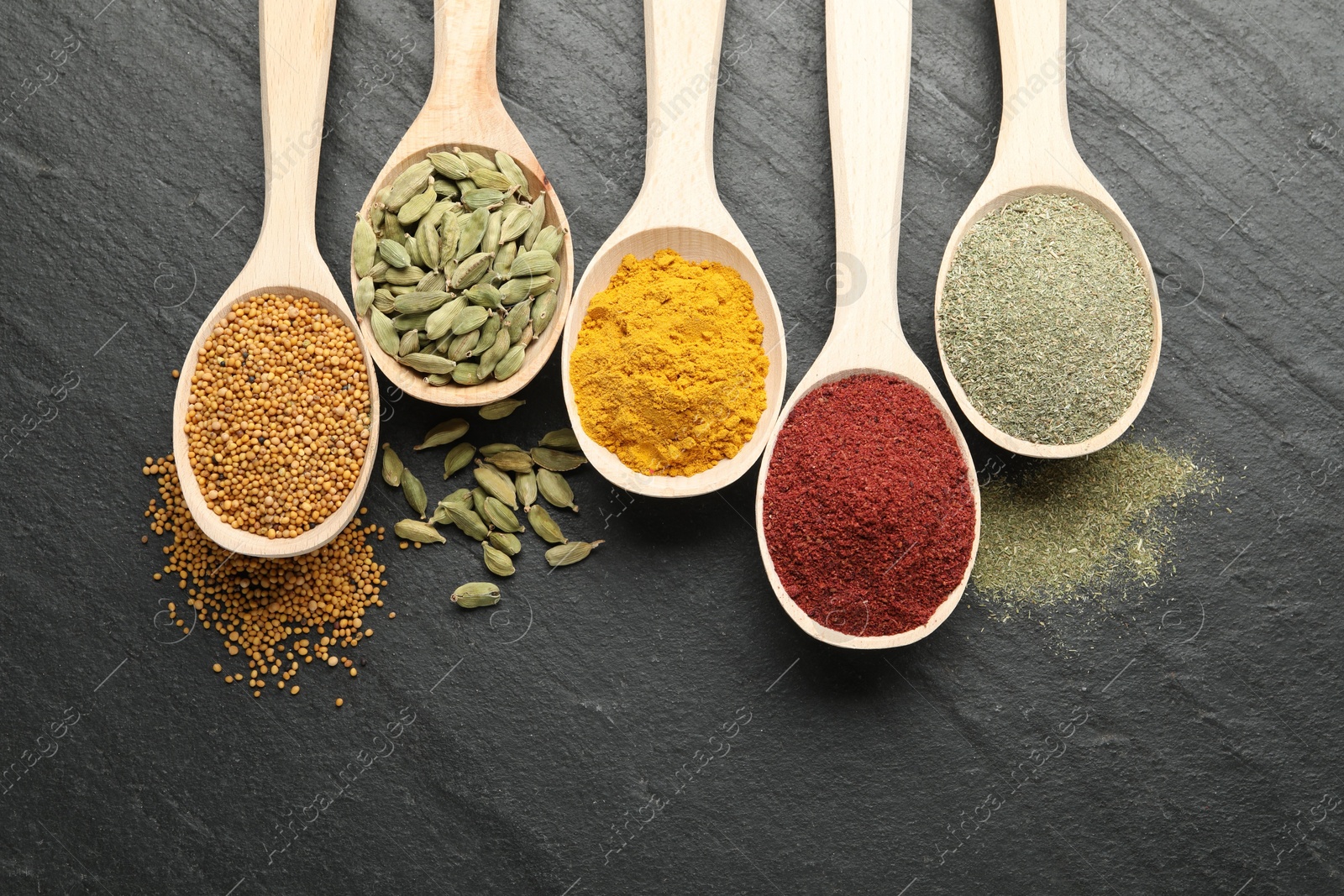 Different aromatic spices in spoons on black table, flat lay Photo of Different aromatic spices in spoons on black table, flat lay
