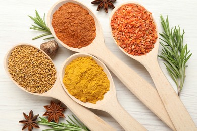 Photo of Different aromatic spices in spoons on white wooden table, flat lay