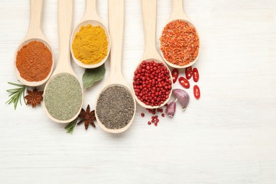 Photo of Different aromatic spices in spoons on white wooden table, flat lay