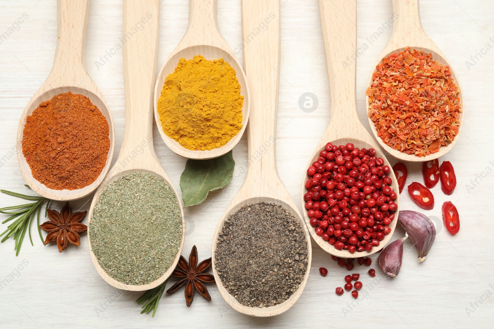 Different aromatic spices in spoons on white wooden table, flat lay Photo of Different aromatic spices in spoons on white wooden table, flat lay