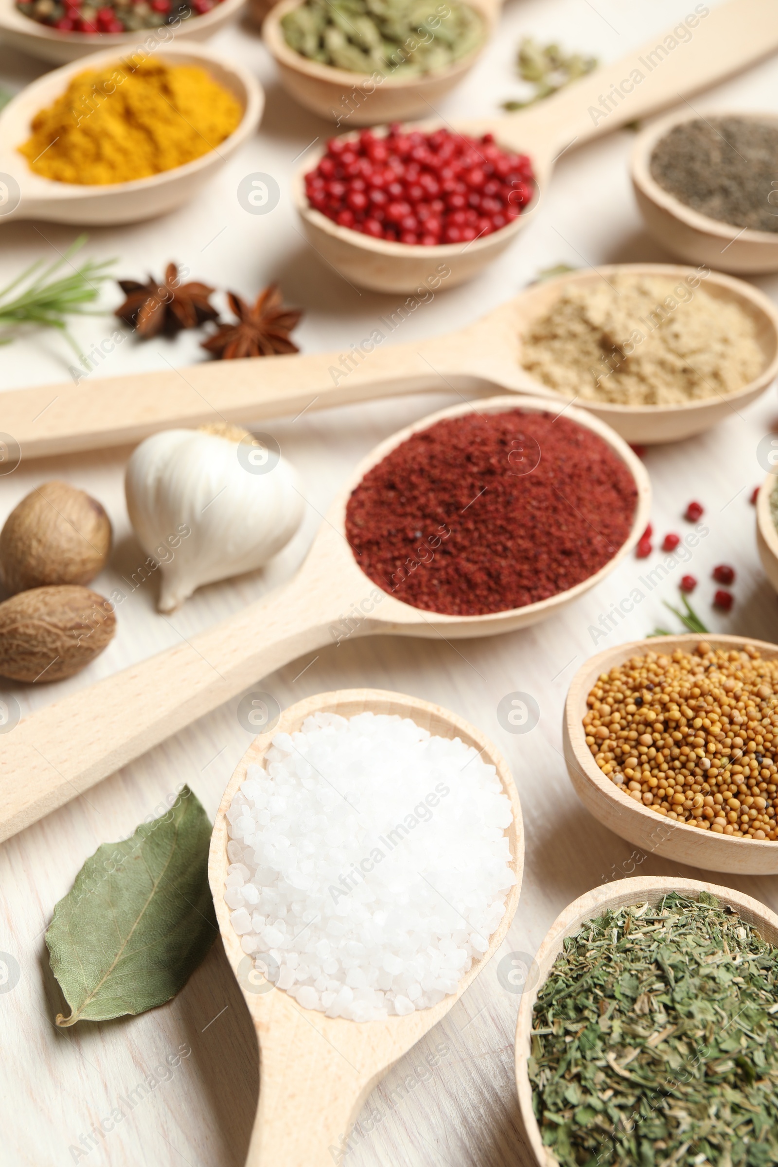 Different aromatic spices in spoons on white wooden table, closeup Photo of Different aromatic spices in spoons on white wooden table, closeup