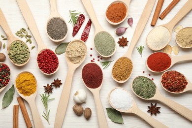 Photo of Different aromatic spices in spoons on white wooden table, flat lay