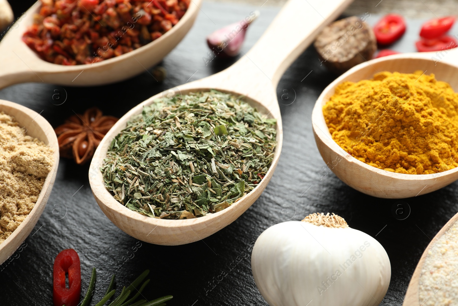 Different aromatic spices in spoons on black table, closeup Photo of Different aromatic spices in spoons on black table, closeup