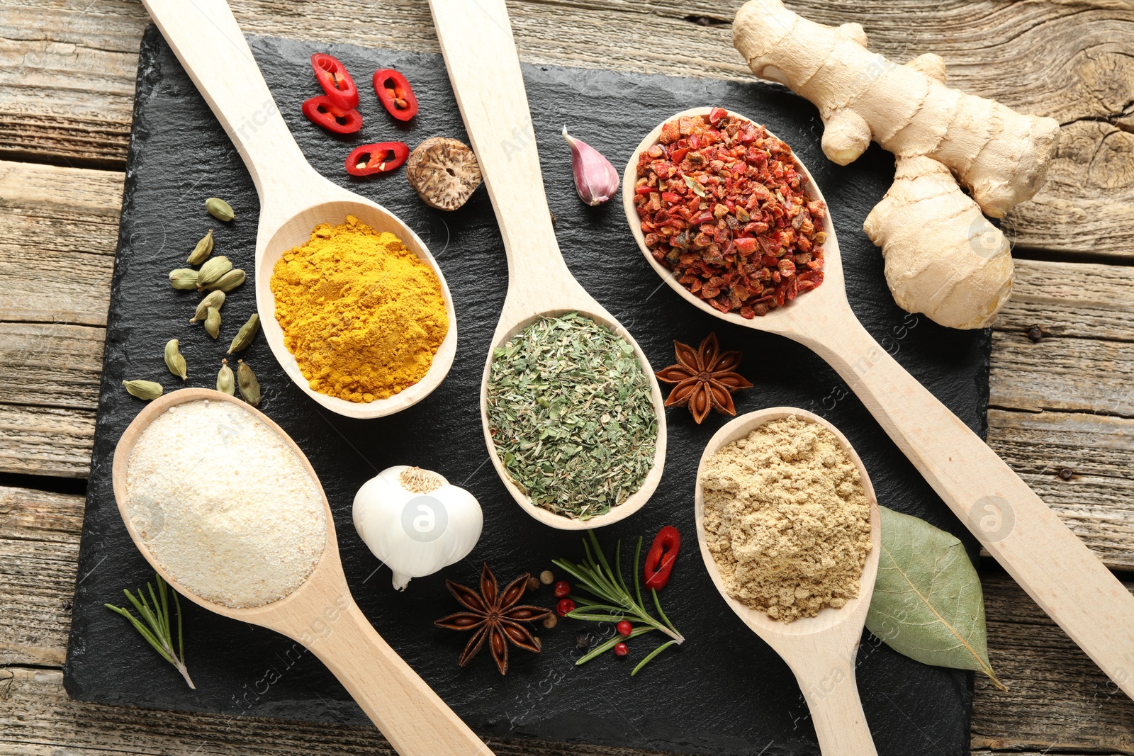 Different aromatic spices in spoons on wooden table, flat lay Photo of Different aromatic spices in spoons on wooden table, flat lay