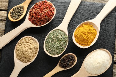 Photo of Different aromatic spices in spoons on wooden table, flat lay