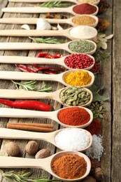 Photo of Different aromatic spices in spoons on wooden table, closeup