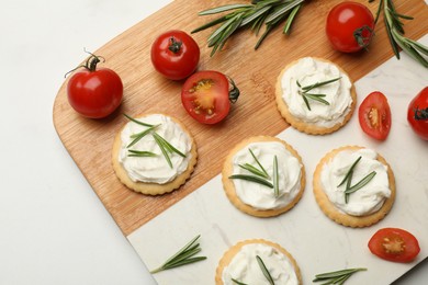 Photo of Tasty crackers with cream cheese, rosemary and tomatoes on white table, top view