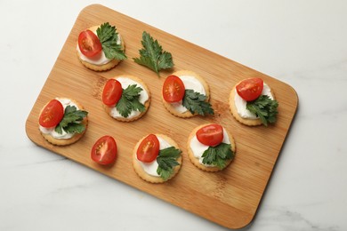 Photo of Tasty crackers with cream cheese, tomatoes and parsley on white table, top view