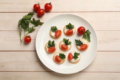 Photo of Tasty crackers with cream cheese, tomatoes and parsley on white wooden table, flat lay