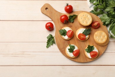 Photo of Tasty crackers with cream cheese, tomatoes and parsley on white wooden table, flat lay. Space for text